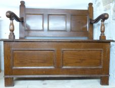 An oak settle or hall seat with panelled decoration and scrolling arms, W107 x D43 x H98cm
