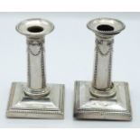 Victorian pair of hallmarked silver candlesticks with embossed swag decoration, London 1895 and 1897