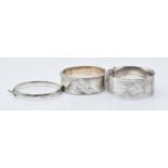 Three hallmarked silver bangles, all with engraved floral decoration, 89g