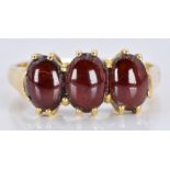 An 18ct gold ring set with three garnet cabochons, 3.6g, size M
