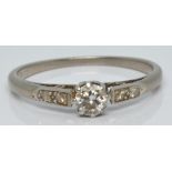 A platinum ring set with a diamond of approximately 0.2ct with further diamonds to the shoulders,