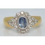 An 18ct gold ring set with an oval cut sapphire surrounded by diamonds, 5.0g, size N/O