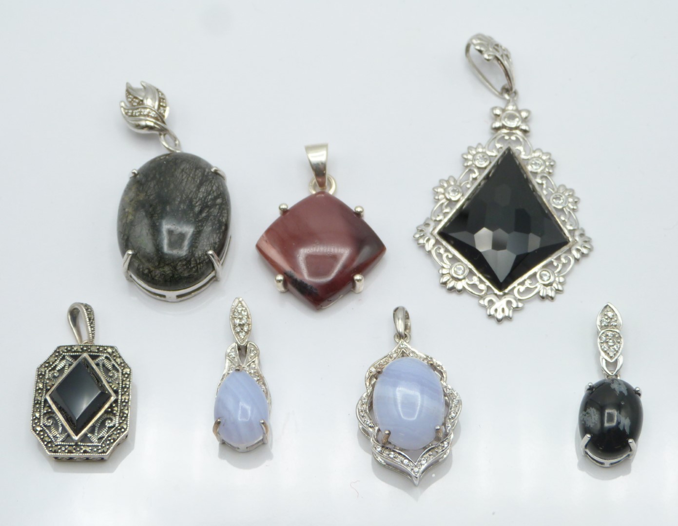Seven silver pendants including set with rutile quartz, onyx, marcasite, obsidian and blue lace