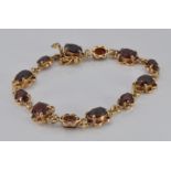 A 9ct gold bracelet set with oval cut garnets, 11.9g