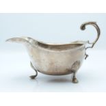 Victorian hallmarked silver gravy boat with scrolling handles and raised on three hoof feet, Chester