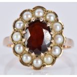 A 9ct gold ring set with an oval garnet surrounded by pearls, 3.8g, size L