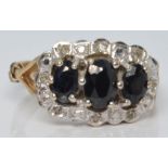 A 9ct gold ring set with three oval cut sapphires surrounded by diamonds, 2.8g, size N