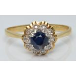An 18ct gold ring set with a round cut sapphire surrounded by diamonds, 2.8g, size O