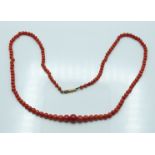 A beaded coral necklace with yellow metal clasp