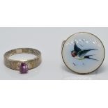 A silver brooch set with enamel depicting a swallow and a silver ring set with a pink sapphire