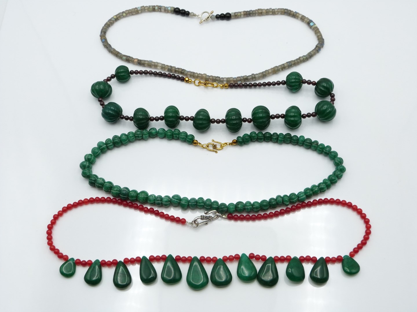 A labradorite necklace, jade and quartz necklace, garnet and quartz and another quartz necklace