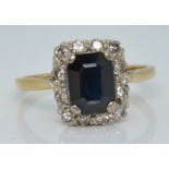 An 18ct gold ring set with an emerald cut sapphire and diamonds, 3.4g, size P