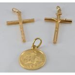 An 18ct gold cross, an 18ct gold St Christopher (4.8g) and a yellow metal crucifix (1.6g)