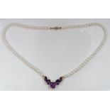 A cultured pearl necklace with a 10k gold section set with amethysts