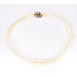 A two strand cultured pearl necklace, the 9ct gold clasp set with garnets and a pearl