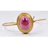 Victorian Etruscan Revival bangle set with a garnet cabochon and sphere and detailed border, 11.