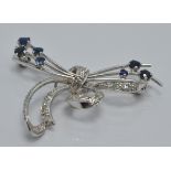 A platinum brooch set with sapphires and diamonds in a stylised bow design, 4 x 2.5cm