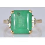 An 18ct gold ring set with a natural emerald cut emerald of approximately 5.97ct and three
