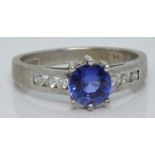 An 18ct white gold ring set with a round cut tanzanite and diamonds to the shoulders, with