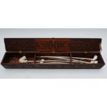 A 19thC pokerwork decorated clay pipe box with long clay pipes within, the box W66 x D9.5 x H10cm,