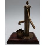 Brass Sanders patent miniature novelty village water pump with bucket below, on wooden base,