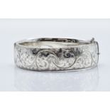 A hallmarked silver bangle with engraved scrolling decoration, 50g