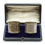 A cased pair of Victorian hallmarked silver napkin rings decorated with classical scenes in relief