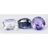 A loose purple sapphire and two blue sapphires