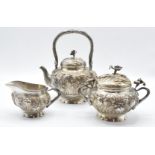 Chinese white metal three piece teaset with embossed iris decoration and flower handles, marked to