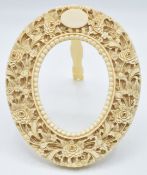 A late 19th/ early 20thC ivory photograph frame with carved floral decoration with easel back, 12.