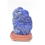 Chinese lapis lazuli carving of a mountainous scene on wooden stand, 18 x 12cm