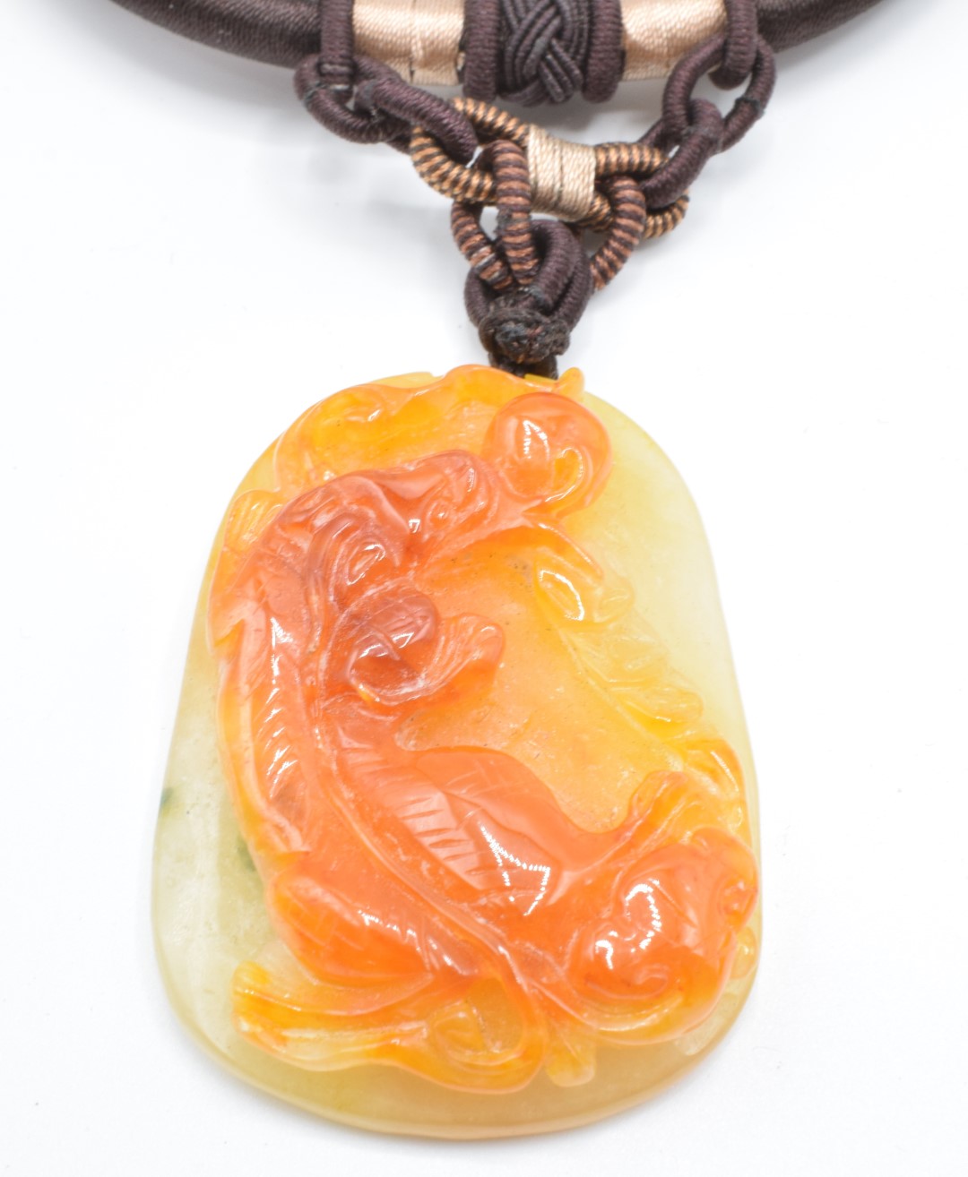 Two Chinese orange jade pendants, one depicting a creature (5.5 x 3.8cm) and the other peaches, 4.