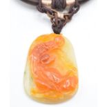 Two Chinese orange jade pendants, one depicting a creature (5.5 x 3.8cm) and the other peaches, 4.