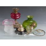 Two brass oil lamps including one with red glass globe and a further green lobed glass shade.