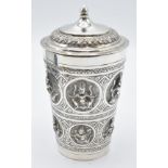 Indian white metal lidded beaker with embossed deity decoration, 13cm tall, weight 147g