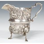 Edward VII hallmarked silver jug with embossed decoration, raised on three feet, Birmingham 1904,