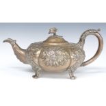 Victorian hallmarked silver squat teapot raised on four feet with repoussé decoration and flower