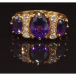 An 18ct gold ring set with three oval cut amethysts and diamonds, size L, 4.4g