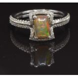 An 18ct white gold ring set with an Australian opal surrounded by diamonds and with further diamonds