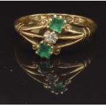 An 18ct gold ring set with a round cut diamond and two square cut emeralds, Chester 1915, size M,