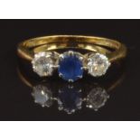 An 18ct gold ring set with an oval cut sapphire of approximately 0.4ct and two diamonds, each