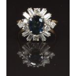 An 18ct gold ring set with an oval cut sapphire surrounded by baguette and round cut diamonds,