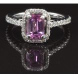 An 18ct white gold ring set with an emerald cut natural pink sapphire surrounded by diamonds, with