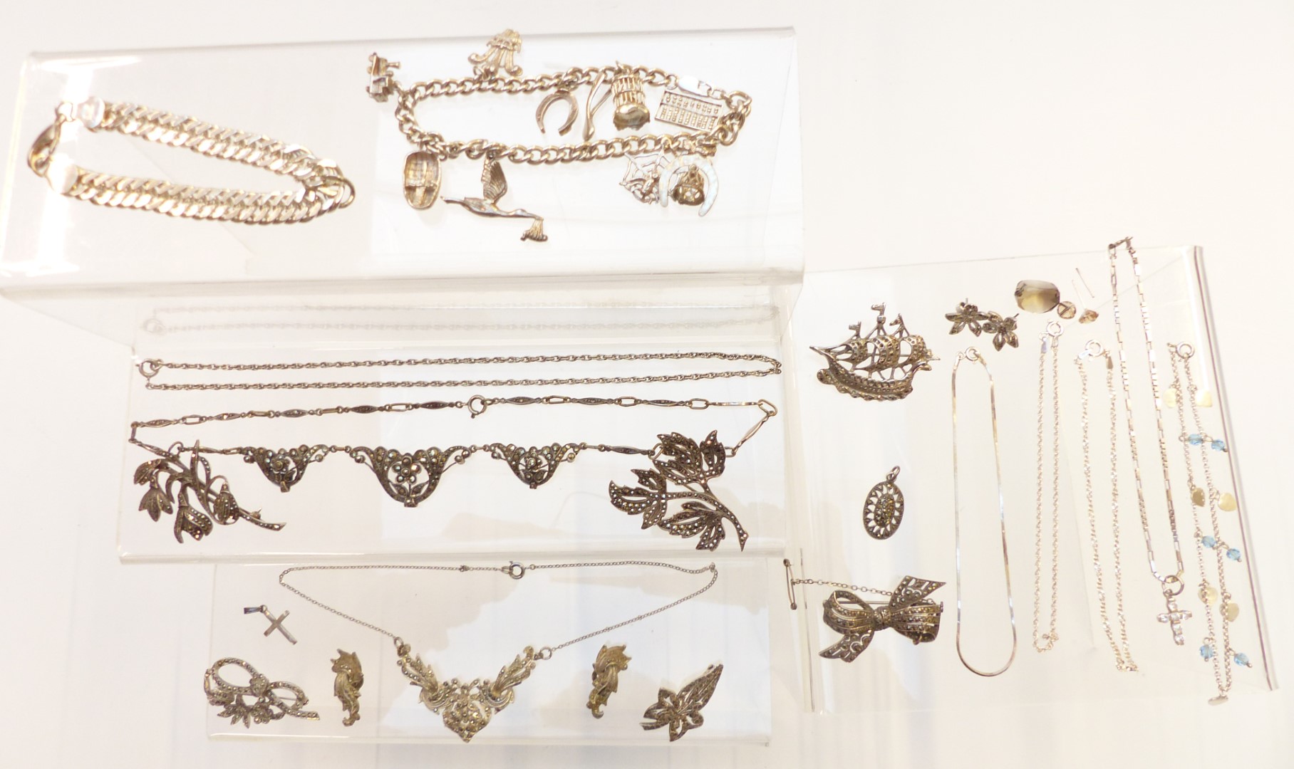 A group of silver jewellery including charm bracelet, curb link bracelet, chains, necklace, brooches