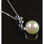 An 18ct white gold pendant set with a faux pearl and sapphires on an 18ct white gold chain, 5.2g,