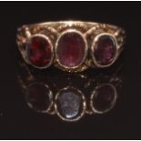 An early Victorian rose gold ring set with three oval cut foiled garnets, size N, 2.3g