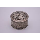 An Indo Persian white metal cylindrical lidded box, decorated hunting scenes, 8.5cm diameter.