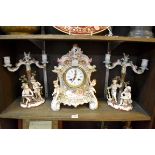 A German porcelain mantel clock, 32.5cm high; together with a similar pair of Sitzendorf figural