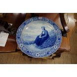 A Dutch Delft blue and white charger, painted with a lady, after Adolph Artz, 41cm diameter.