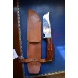 A Remington Dupont hunting knife, having 15cm blade, in leather sheath.